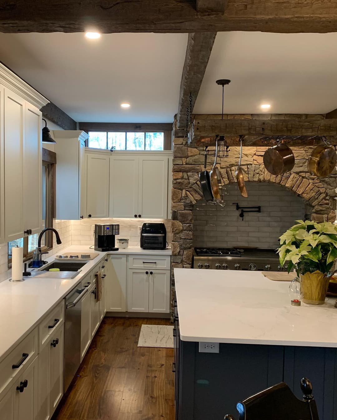 Modern rustic kitchen featuring stone accents, white cabinetry, and stainless steel appliances.