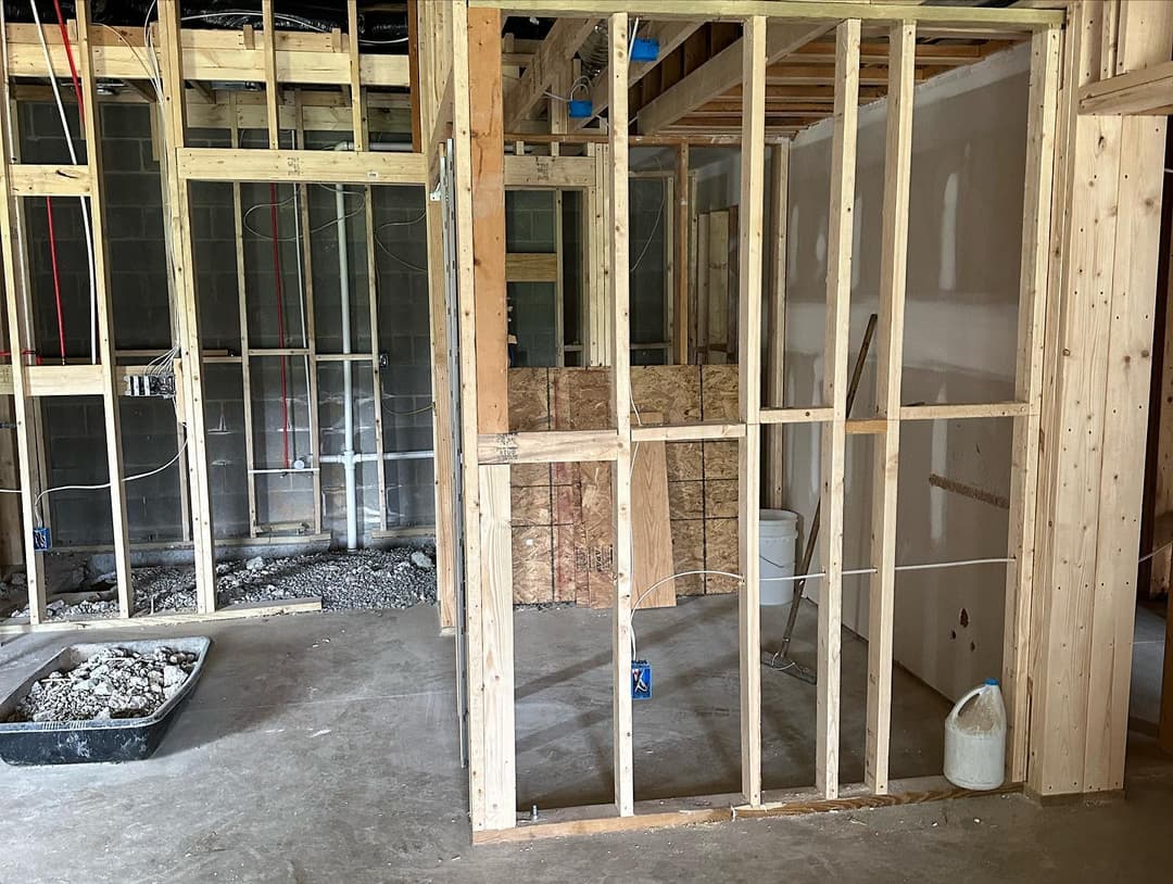 Interior construction site with framed walls and exposed plumbing, showing progress on renovations.