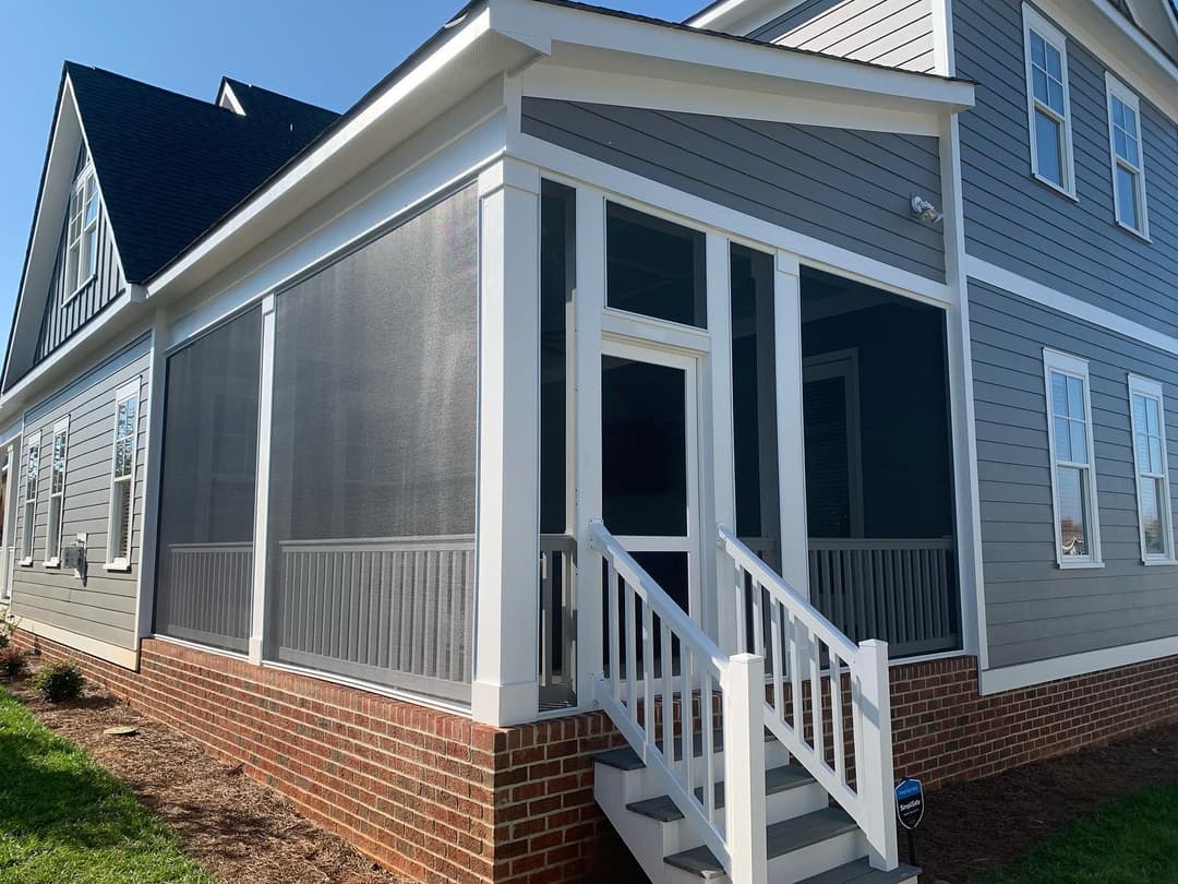 Modern screened porch addition with white railings next to a stylish gray home.