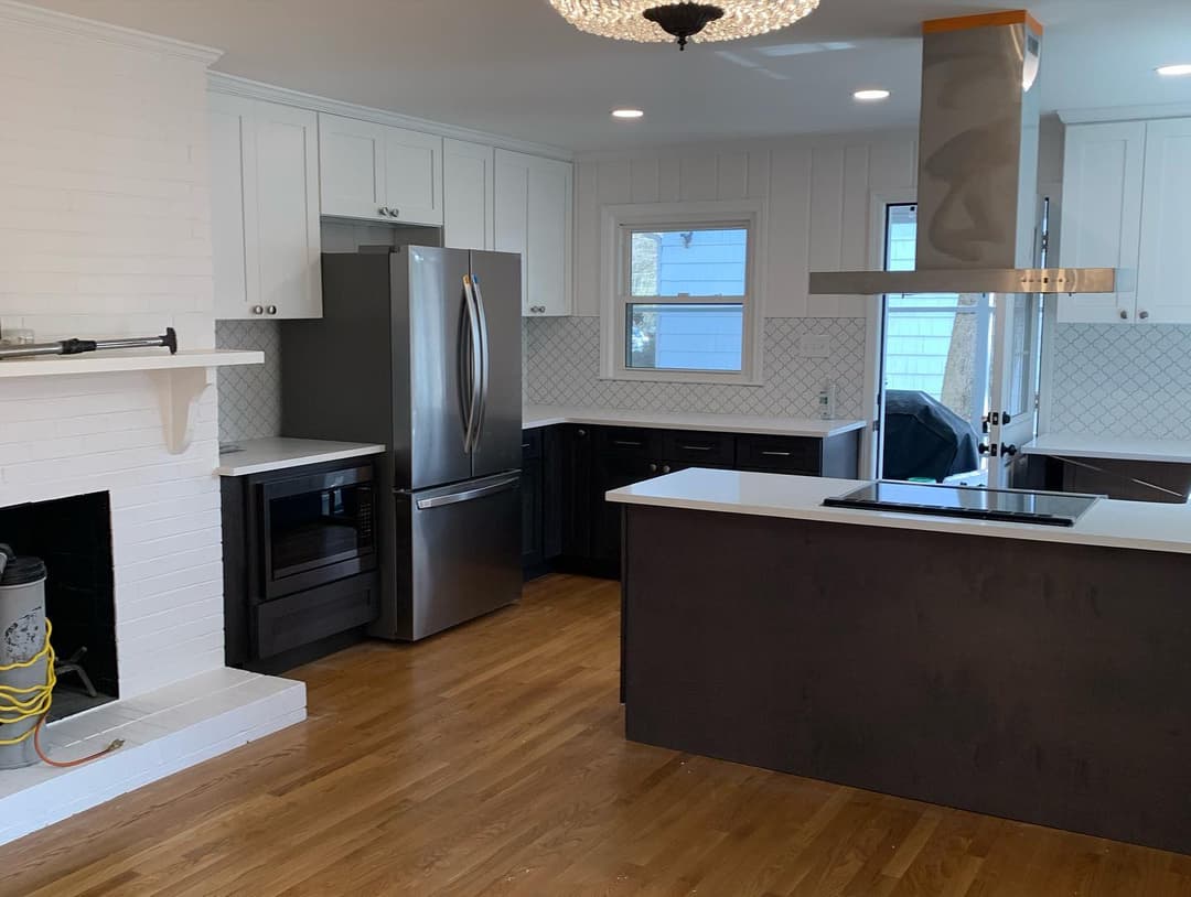 Modern kitchen with stainless steel appliances, white cabinets, and hardwood flooring.