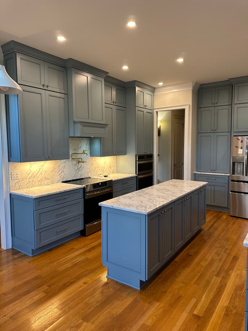Modern kitchen with blue cabinetry, marble countertops, and stainless steel appliances.