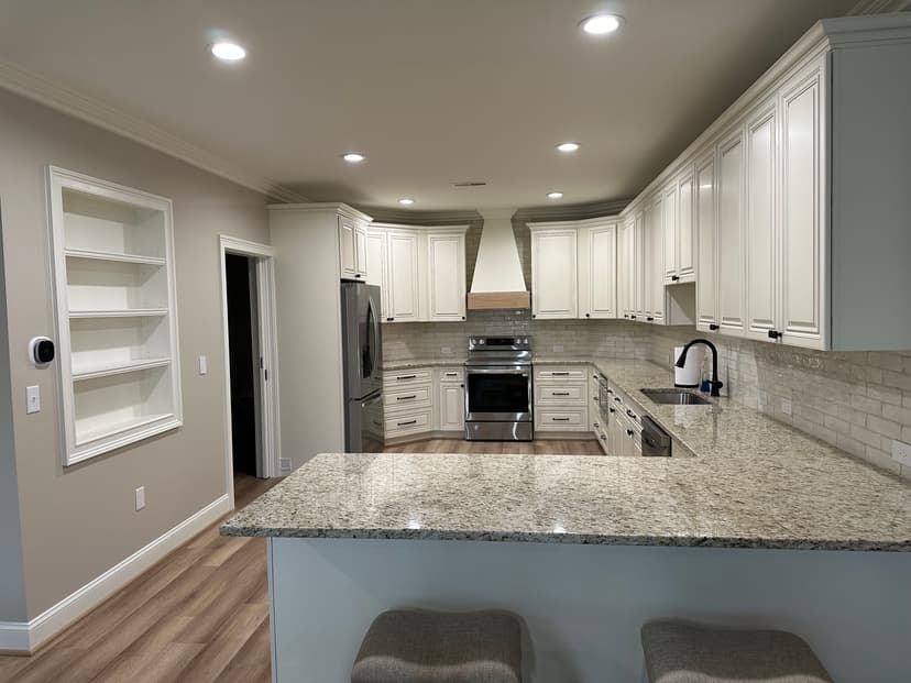 Modern kitchen featuring white cabinets, granite countertops, and stainless steel appliances.