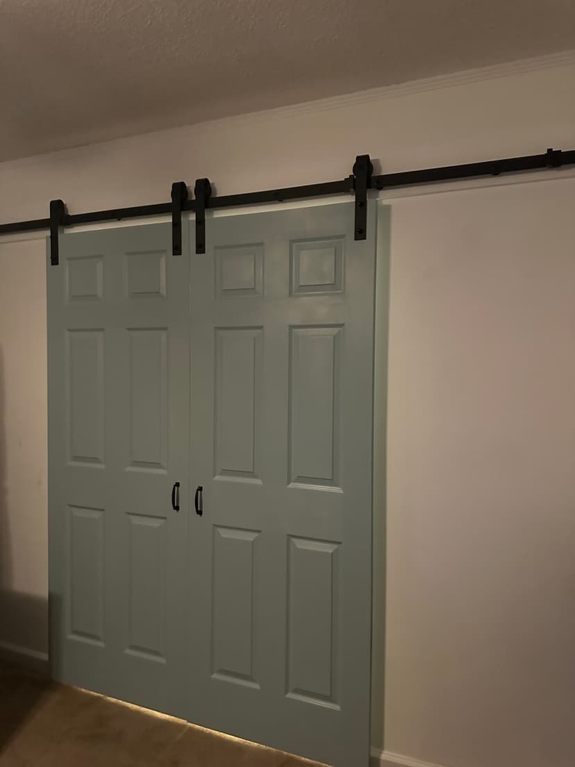 Sliding barn doors with a modern design in a light blue color against a white wall.