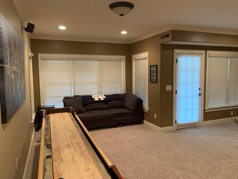Cozy home interior featuring a shuffleboard table, sofa, and large windows with blinds.