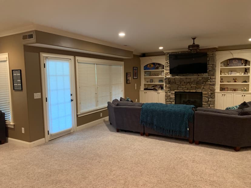 Cozy living room featuring a stone fireplace, comfy couches, and large windows.