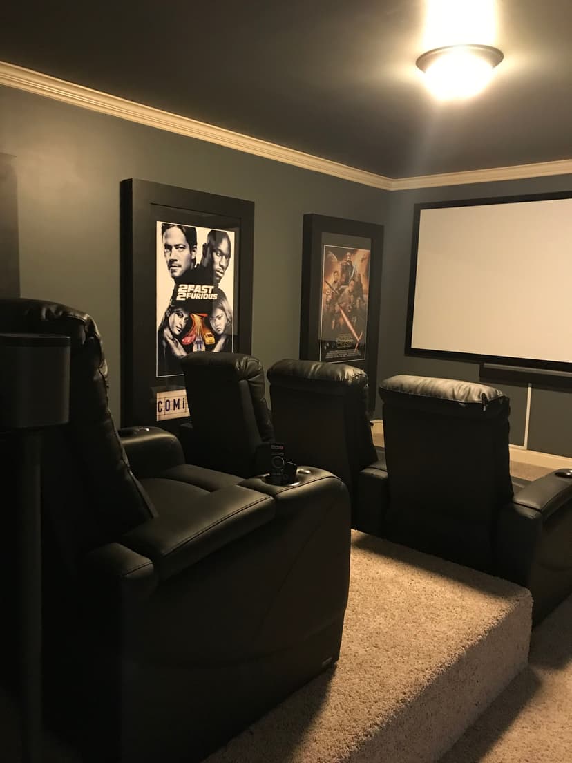 Home theater setup featuring leather recliners, movie posters, and a large screen.