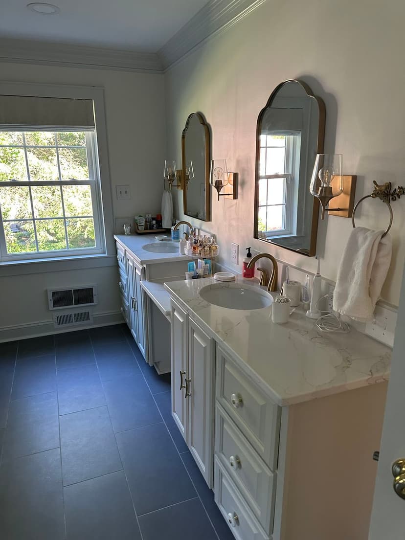 Bright, modern bathroom with dual vanities, large mirrors, and natural light from window.